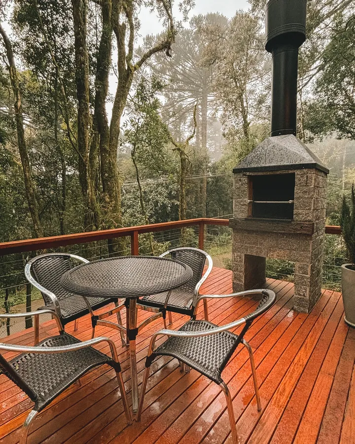 Deck de madeira com mesa, cadeiras e churrasqueira de tijolos